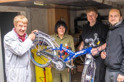 Vier Menschen reparieren ein Fahrrad